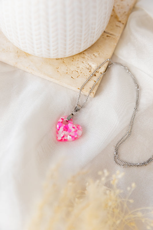 Necklace with a pink heart-shaped pendant on a white surface
