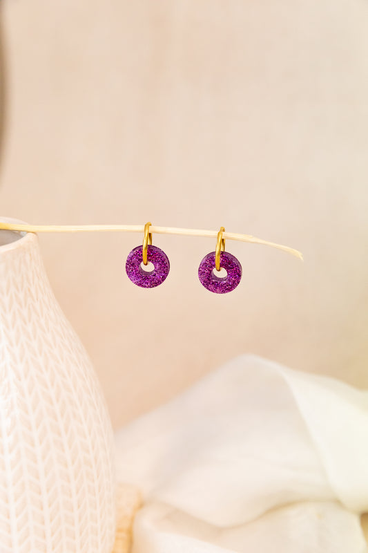 Purple earrings on a beige background