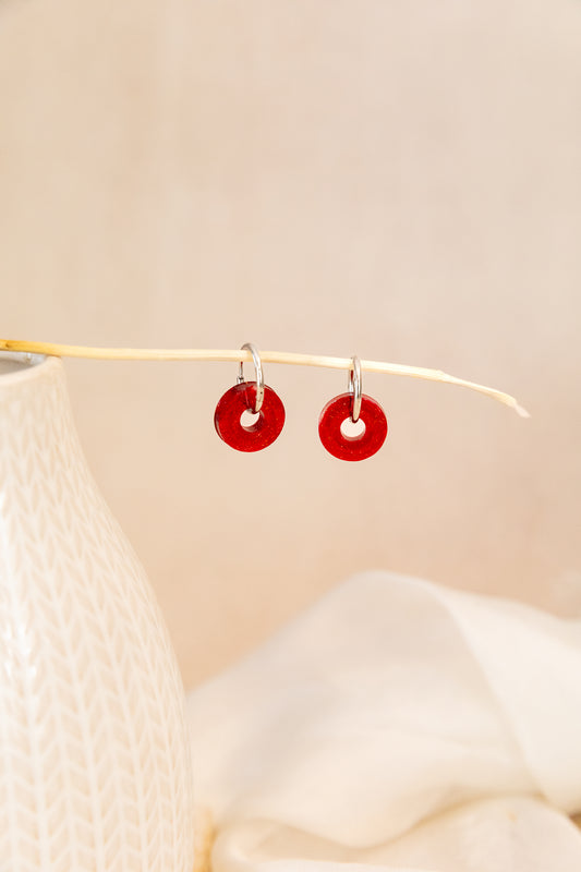 Red circular earrings on a beige background
