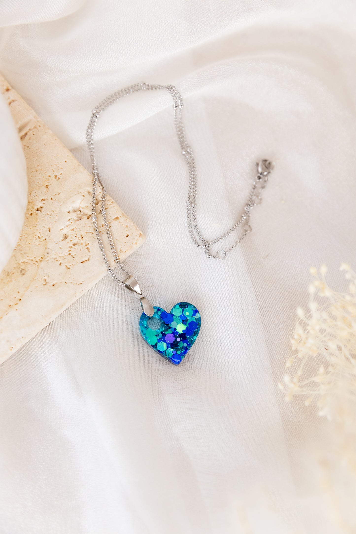 Necklace with a blue heart-shaped pendant on a white fabric background