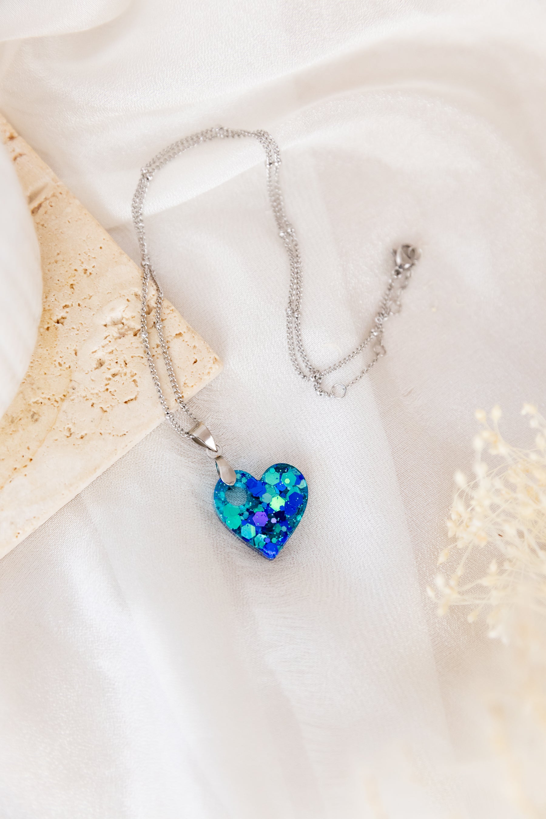 Necklace with a blue heart-shaped pendant on a white fabric background