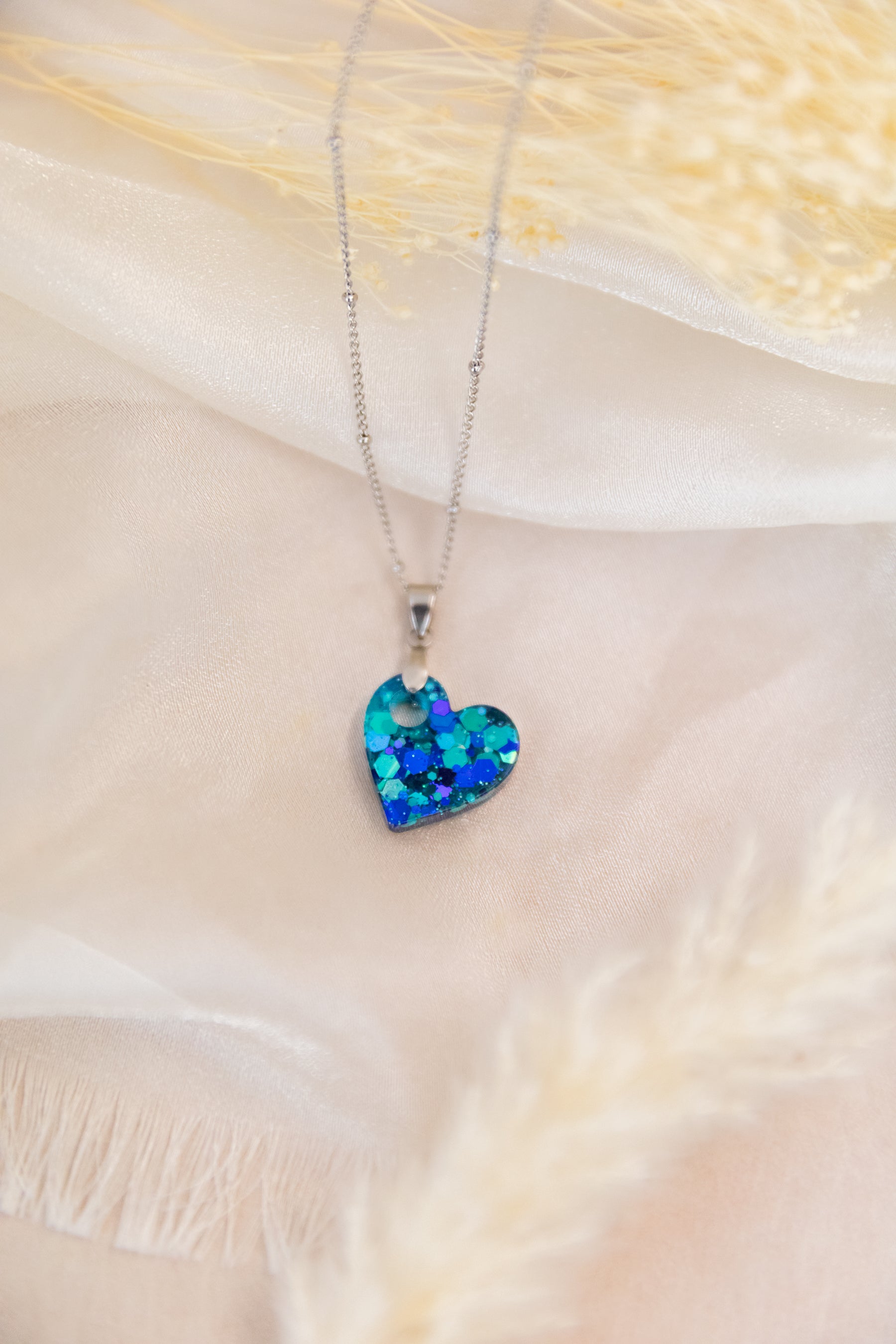 Heart-shaped blue pendant necklace on a soft fabric background
