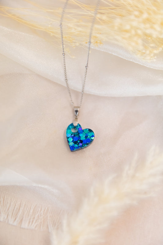 Heart-shaped blue pendant necklace on a soft fabric background