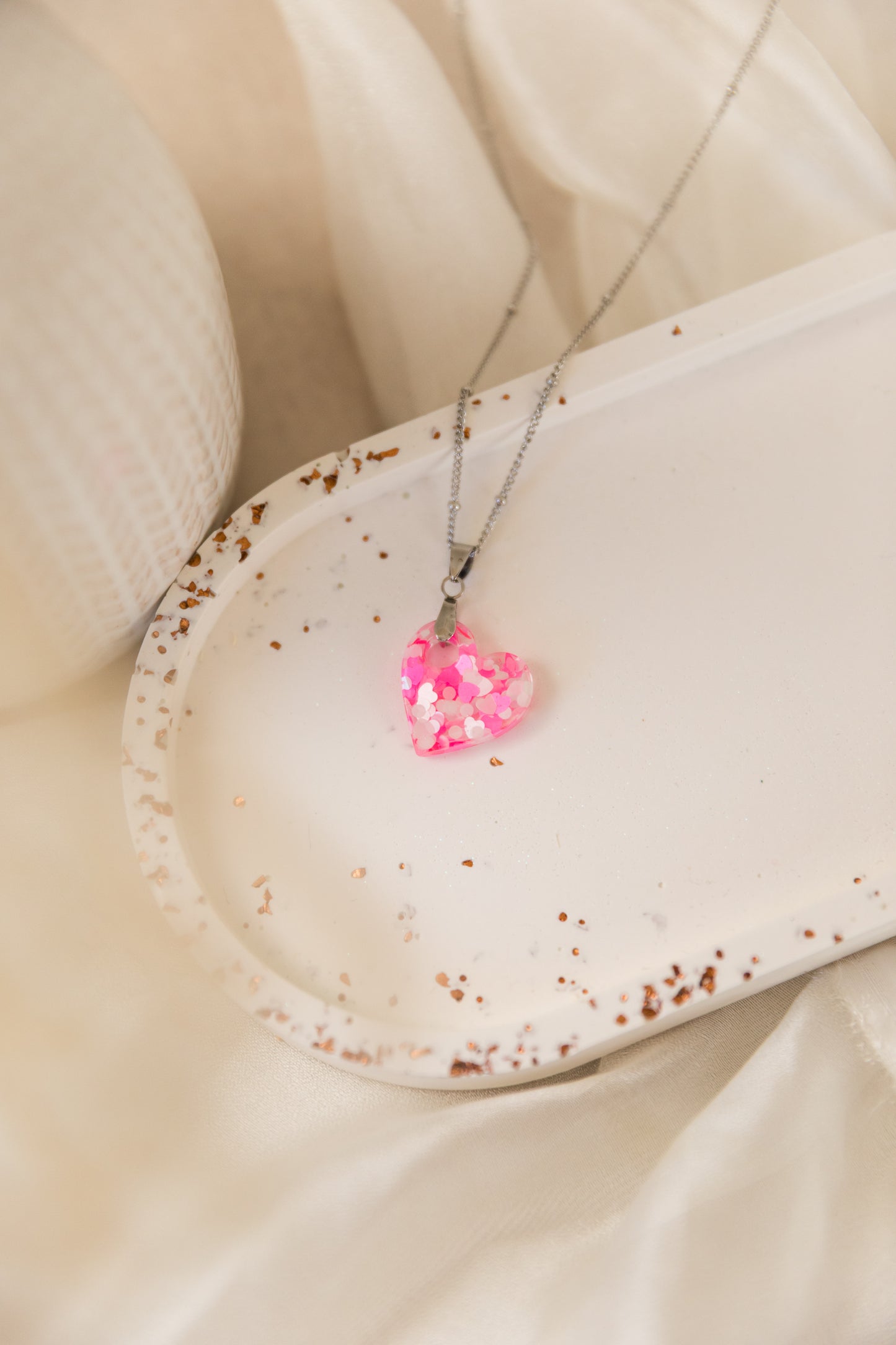 Necklace with a pink heart-shaped pendant on a beige surface