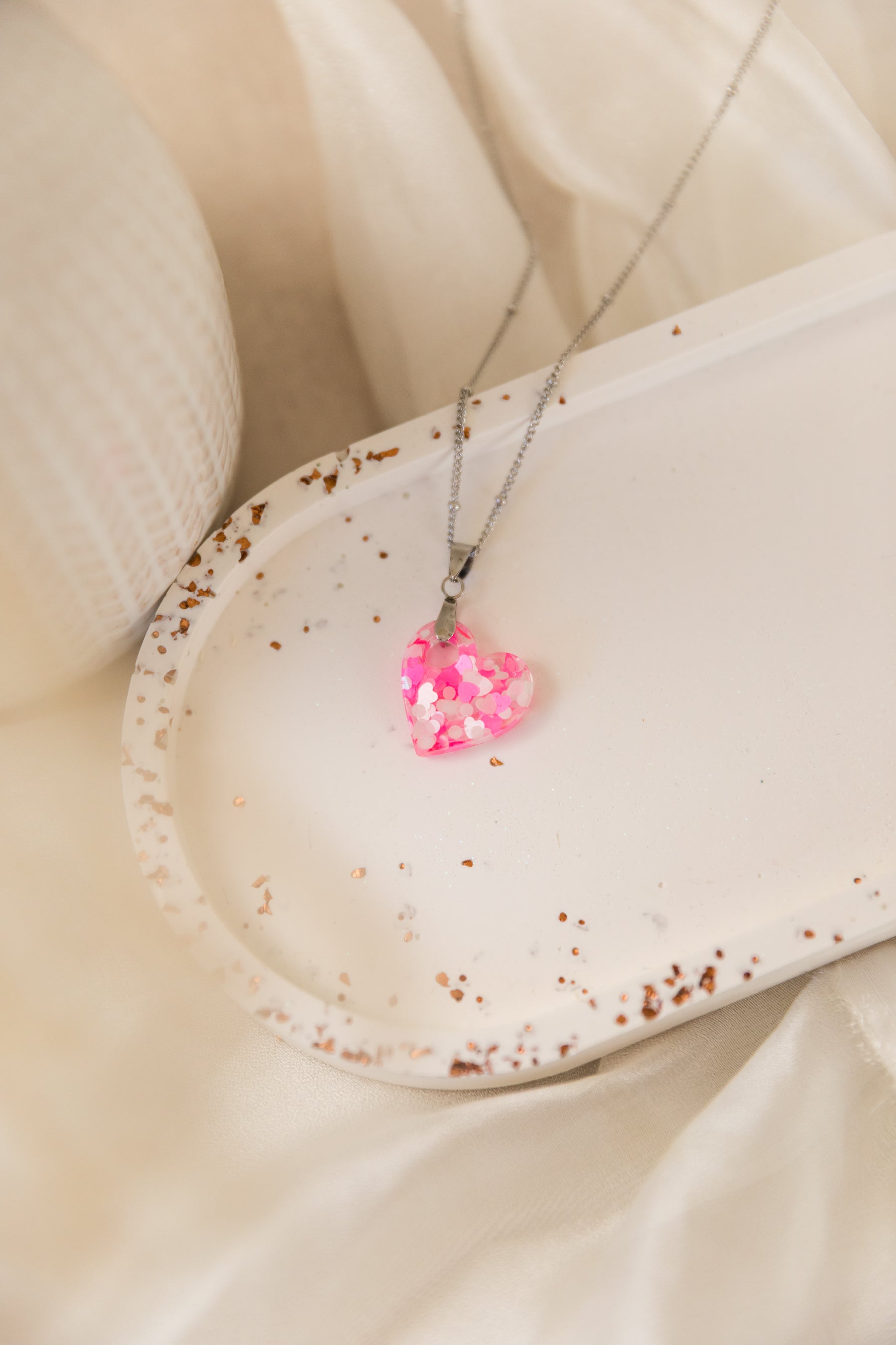 Necklace with a pink heart-shaped pendant on a beige surface