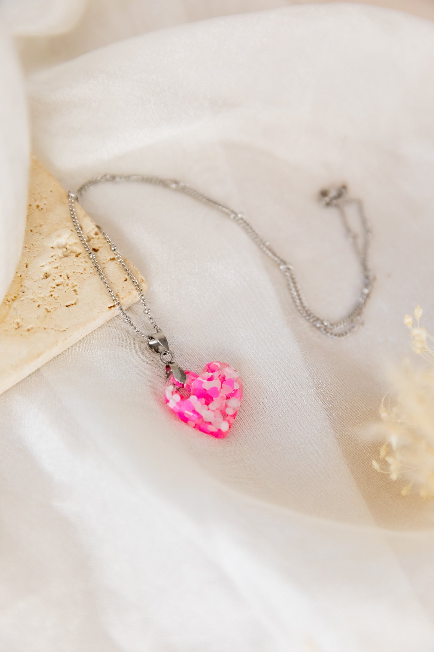 Necklace with a pink heart-shaped pendant on a soft white background