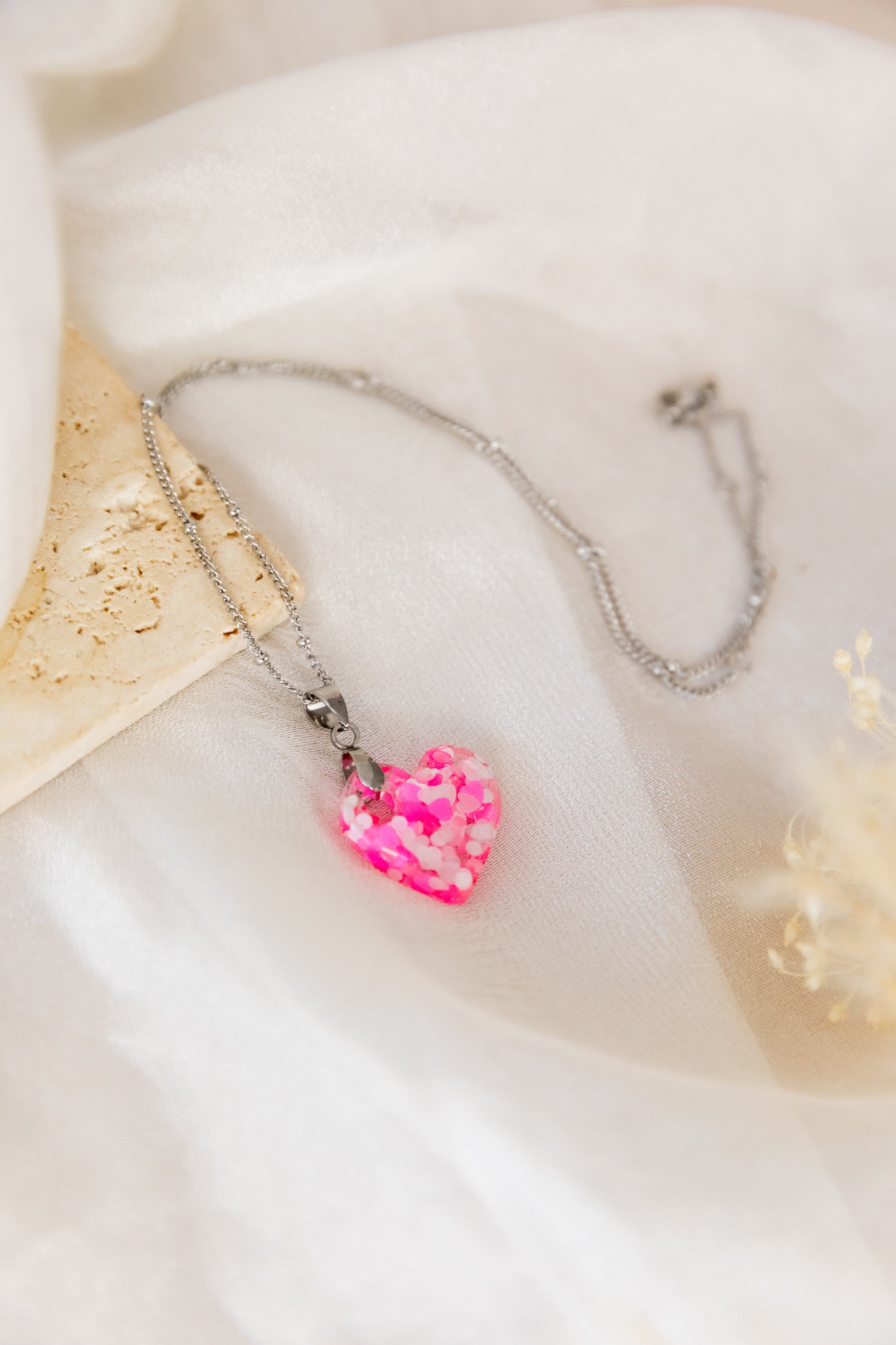 Necklace with a pink heart-shaped pendant on a soft white background