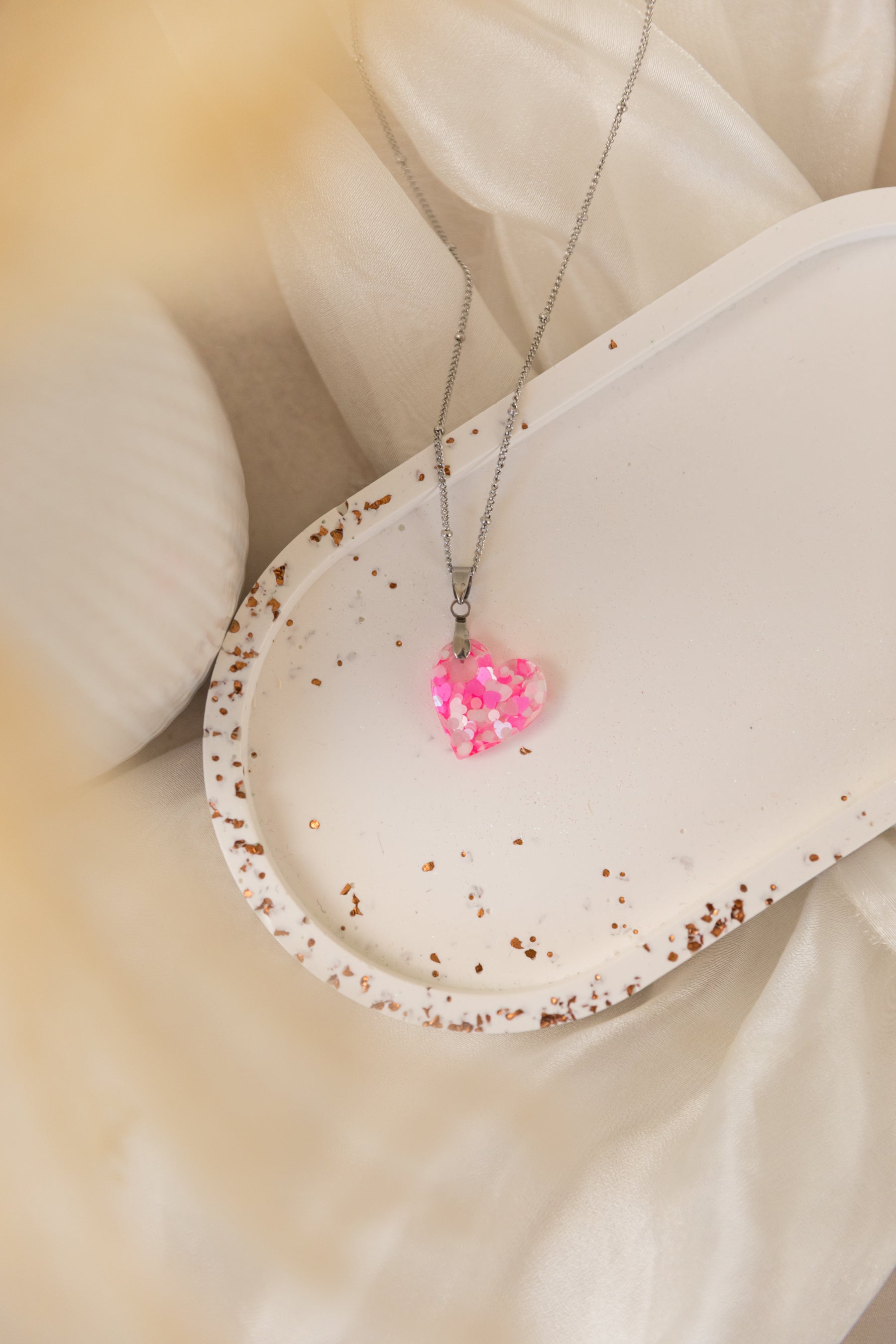 Necklace with a pink heart pendant on a white surface