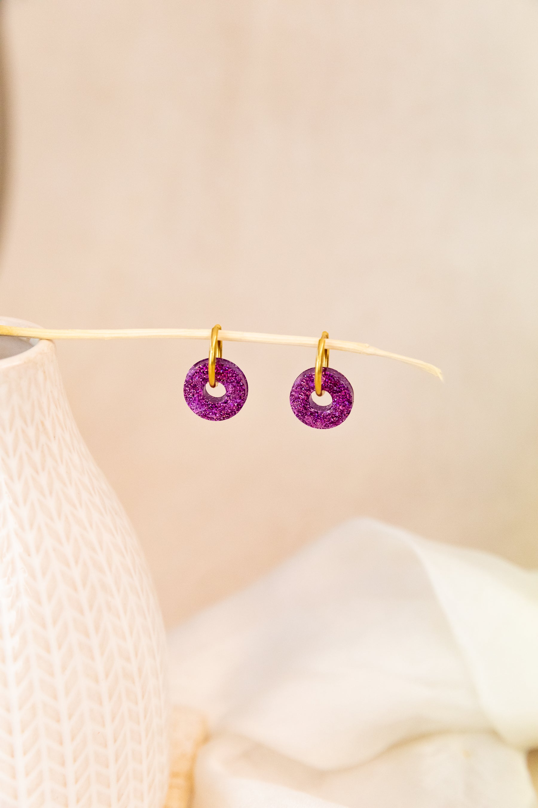 Purple earrings on a beige background