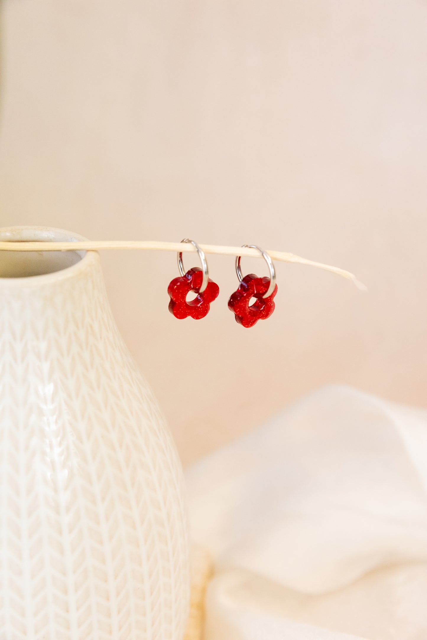 Red floral earrings on a beige background