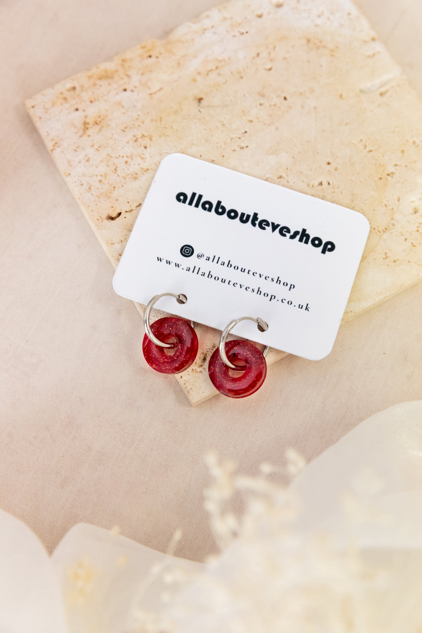 Red circular earrings on a beige card with 'allabouteyeshop' branding.
