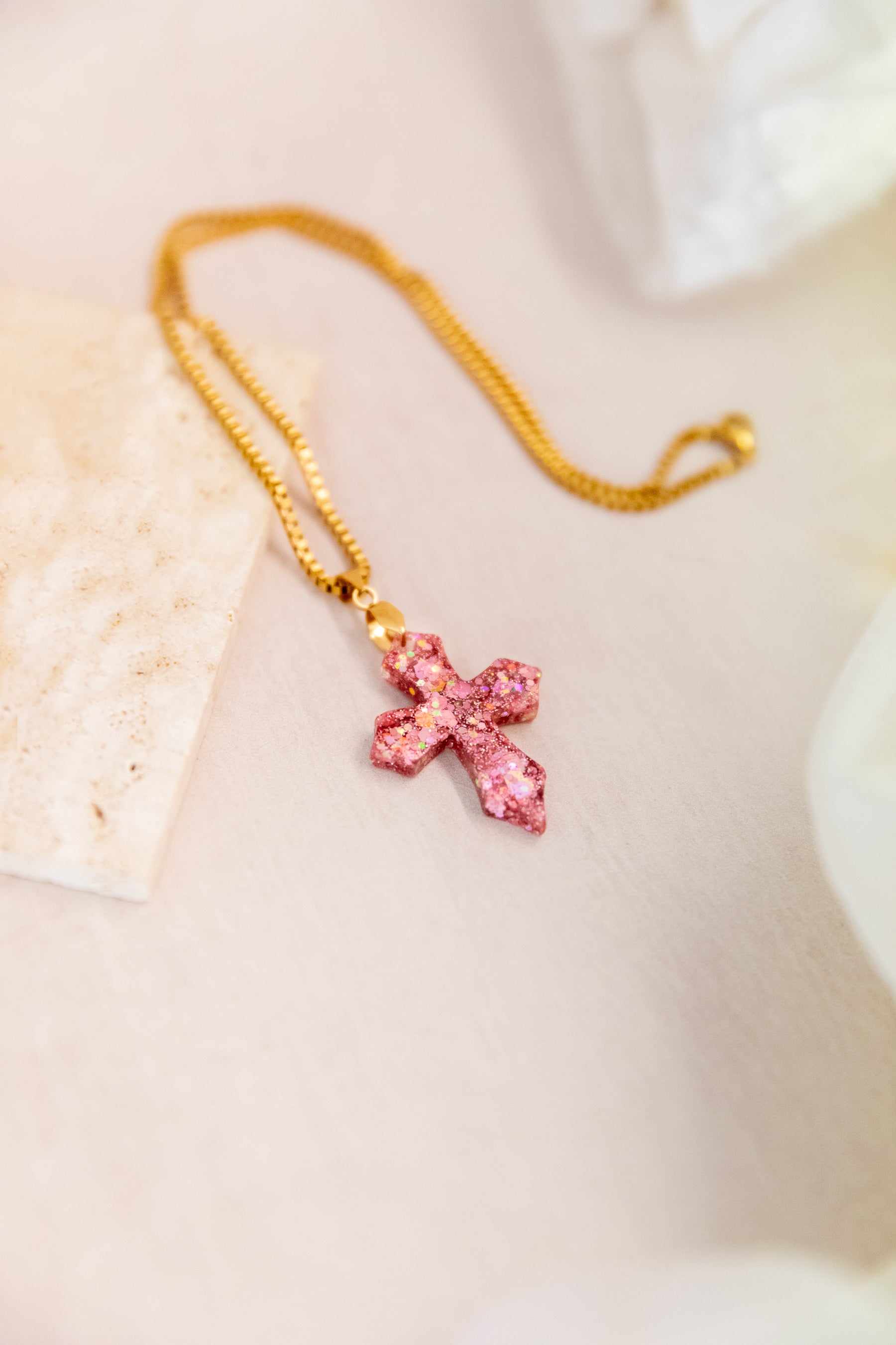 Necklace with a pink cross pendant on a light background