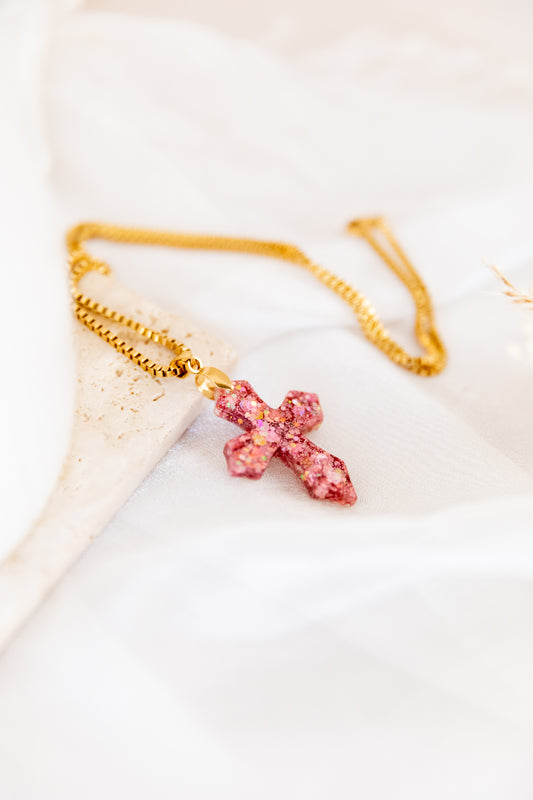 Necklace with a pink cross pendant on a light background