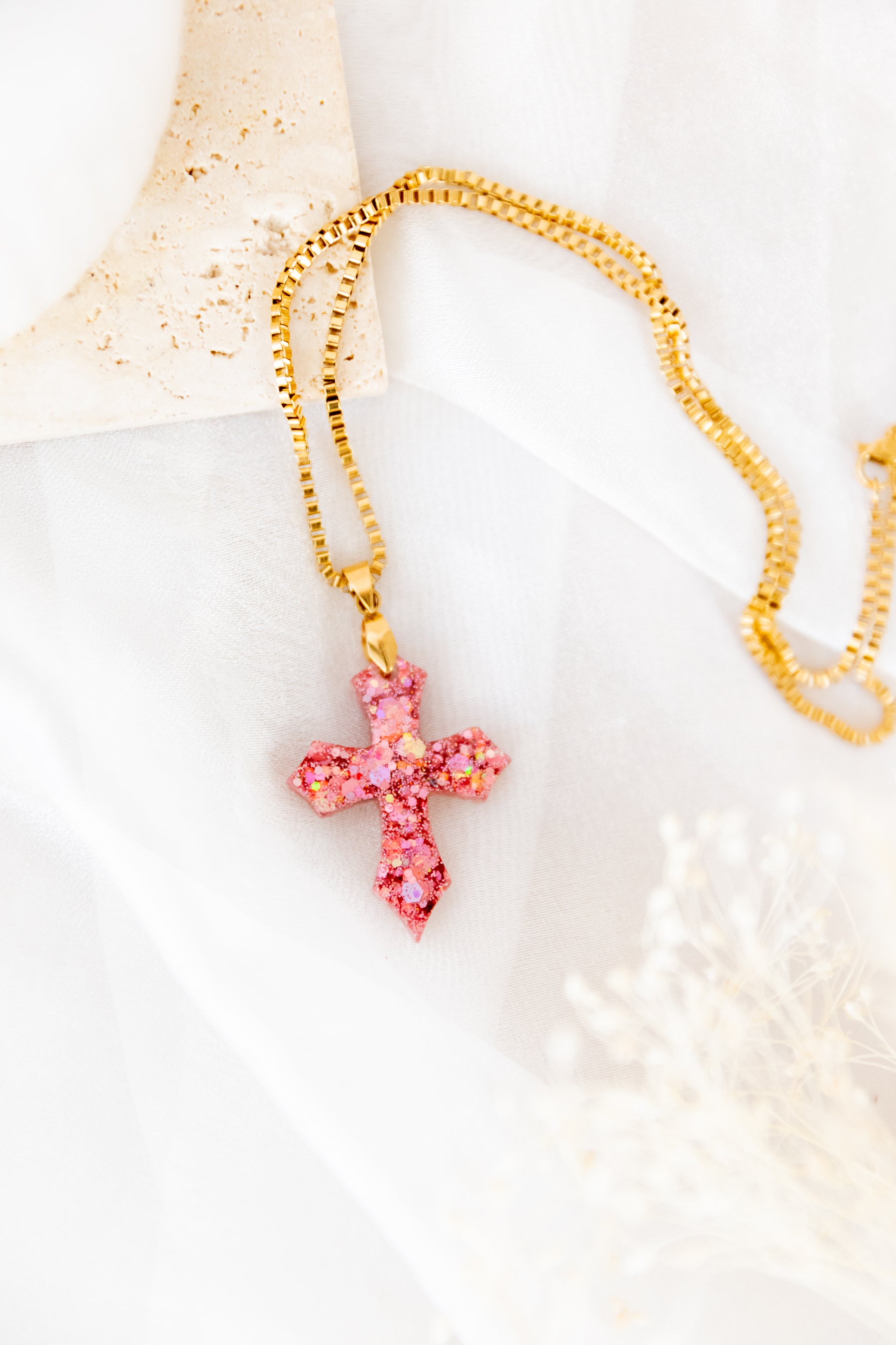 Necklace with a pink cross pendant on a light background